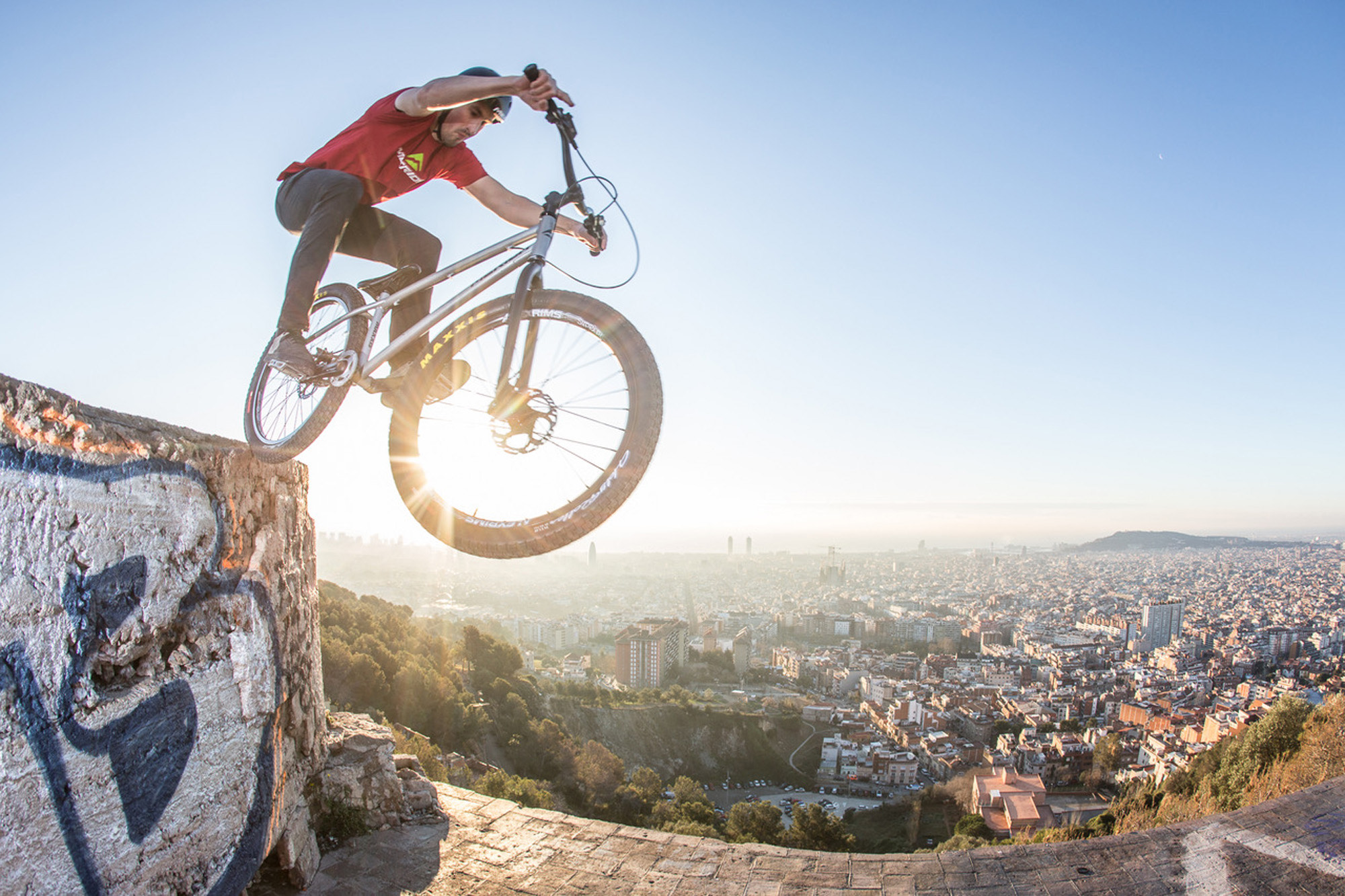Dominik Raab steht mit dem Hinterrad auf einer Mauer über den Dächern von Barcelona