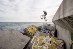 Dominik Raab springt auf Betonwürfel neben dem Meer