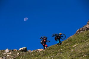 Dominik Raab und Alban Aubert tragen ihre Bikes auf einen Berg hoch