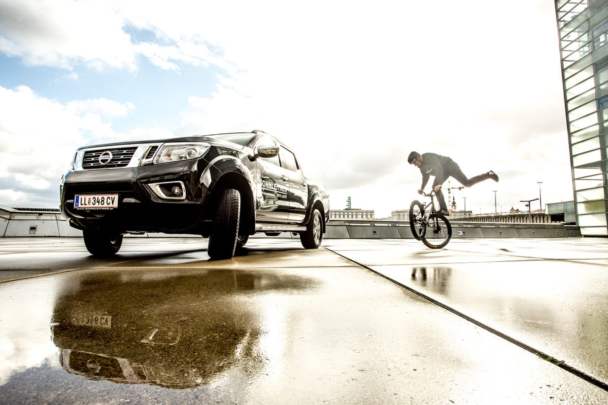 Dominik Raab befindet sich auf seinem Fahrrad beim AEC in Linz und ein Nissan Navara steht neben ihm